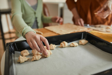 Obraz premium Girl baking at the wooden board while preparing bagels at the kitchen