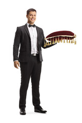 Full length portrait of young man in a suit and bow tie holding a red velvet cushion