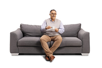 Fototapeta premium Mature man sitting on a sofa with a cup of coffee
