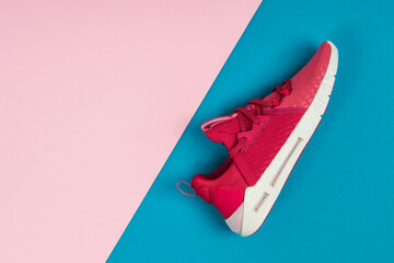 Running sports shoe on blue and pink background. Running shoe, sneaker or trainer. Women's athletic...