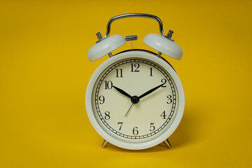 Retro alarm clock on yellow background. Old fashioned alarm clock