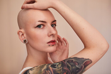 Attractive short haired tattooed woman posing fashionably with hands near her face