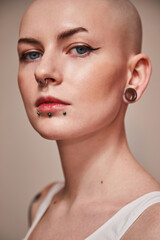 Young woman with tattoos and piercing posing on white background