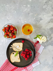 Healthy Breakfast concept, top view, flat lay.
Delicious bread with soft cheese, fresh strawberries, raspberries and green tea
