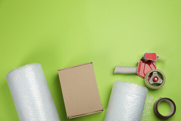 Flat lay composition with bubble wrap rolls on green background, space for text