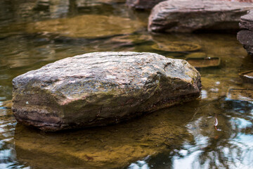 Fototapeta na wymiar Stone sitting in a reflecting pond