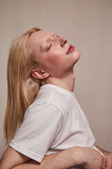 Serene albino and blonde long haired guy posing with closed eyes