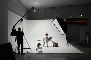 Fashion photography in a photo studio. Professional male photographer taking pictures of beautiful...