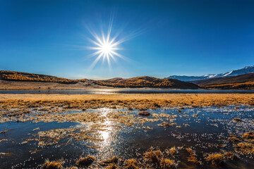 View of Lake Dzhangyskol in the Yeshtykel tract with grass covered with morning frost. Russia, Altai Republic.