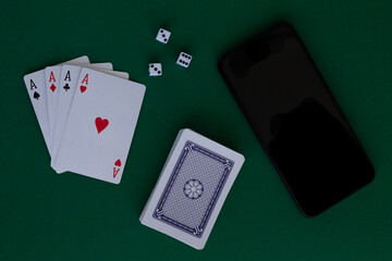 ace of hearts.online poker games. four aces with dice and phone in casino. playing cards with blue deck on the green table. combination of cards on a green casino desk background.copy space. top view