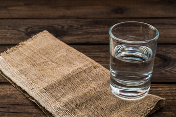 Shot of vodka with piece of cloth on an old wooden table. Close up view
