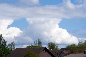 Cloudy sky background at springtime with pitched roof tops in the foreground. Photo taken May 20th, 2021, Zurich, Switzerland.