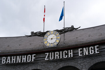 Watch, sculptures and flags at entrance of railway station at City of Zurich. Photo taken May 20th,...
