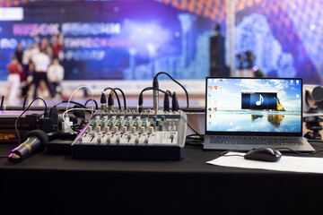 Workplace with audio mixing console, laptop and microphone of sound engineer control music and...