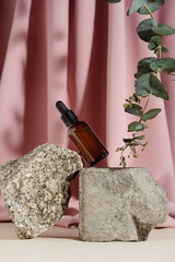 Glass bottle of natural oil or serum on stone bricks with eucalyptus branch