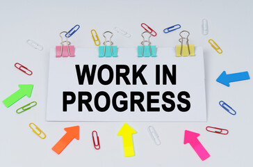 On the table there are paper clips and directional arrows, a sign that says - Work In Progress