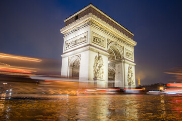 Fototapeta na wymiar Paris, France - February 3, 2017: Paris Arc de Triomphe long exposure artistic image with traffic lights on a rainy night. Majestic Structure
