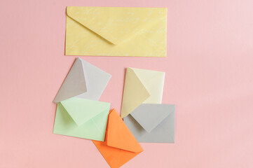 Paper envelopes of different colors on a pink background. View from above