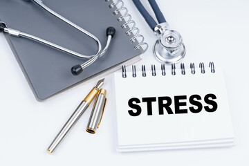 On the table are a stethoscope, a pen and a notebook with the inscription - STRESS
