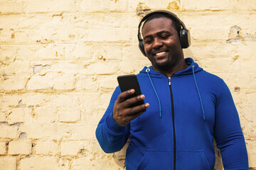 Sporty man with headphones  using mobile phone outdoor.