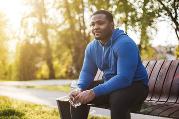Man resting on bench after exercise and  drinking water . - 434797695