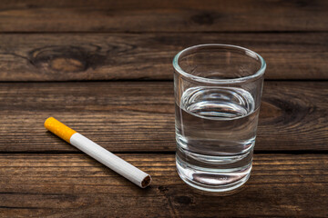 Shot of vodka with cigarette on an old wooden table. Close up view - obrazy, fototapety, plakaty