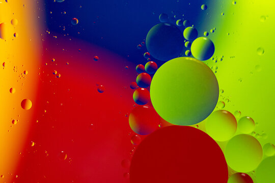 Macro photography of the drops on the water surface.Multicolored vibrant background.Cosmic circles looks like molecule structure.Backdrop with copy space,good as template.