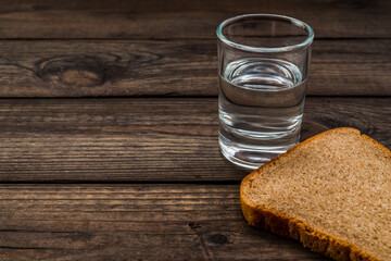 Shot of vodka with a piece of black bread on an old wooden table. Close up view