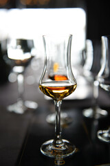 A glass with wiskey on table with blurred background. Concept of whiskey tasting.