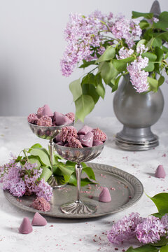 Belgian sweets cuberdon and pralines in silver glasses, spring still life with lilac flowers