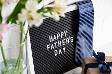 Happy Fathers Day concept. Letterboard with sign Happy Father's Day, gift box, flowers on table.