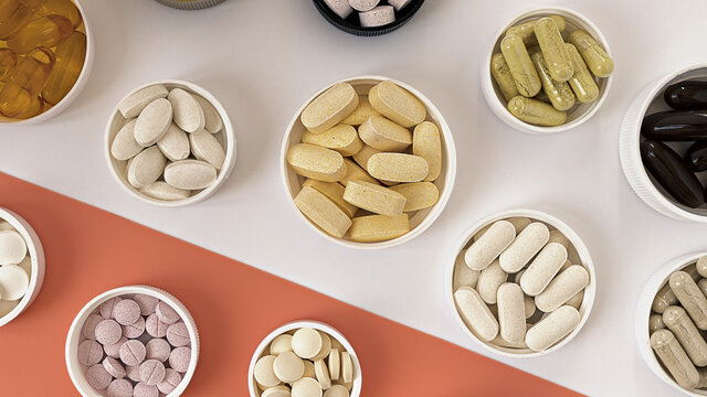 close-up of multivitamin biologically active supplements on white and coral background. mental wellbeing and  personal health concept