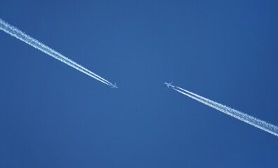 Two airplanes are approaching each other in the blue sky