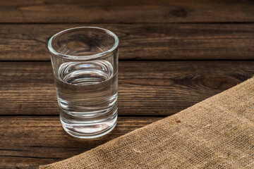 Shot of vodka with piece of cloth on an old wooden table. Close up view