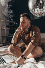 Man inhales a smoke of the hand rolled cigarette while smoking cannabis at home