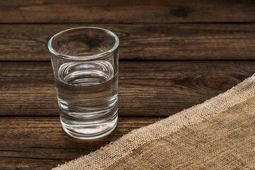 Shot of vodka with piece of cloth on an old wooden table. Close up view