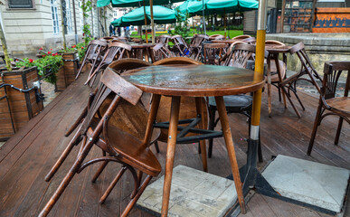 Empty street cafe with small round tables and wooden chairs after rain at the cloudy day