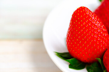Ripe Strawberries in a White Plate. Fresh Juicy Strawberries with Leaves. Summer Berries Background.