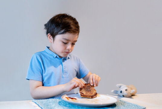 Portrait Healthy Kid eating pork chops for dinner.Hungry Child boy enjoy eating home made grilled steak at home. Healthy food for Children concept