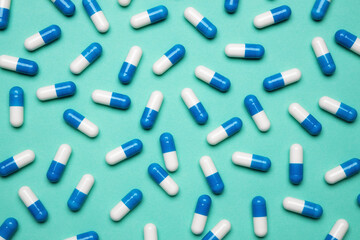 Blue pills on a green background. The concept of taking antibiotics, antidepressants or other medications. Medical background or pharmacy concept.