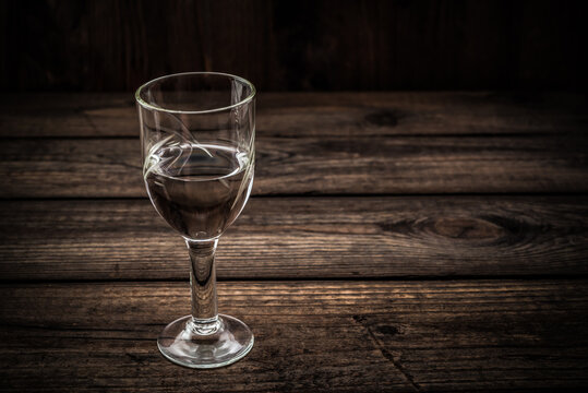 Glass of vodka on an old wooden table. Angle view
