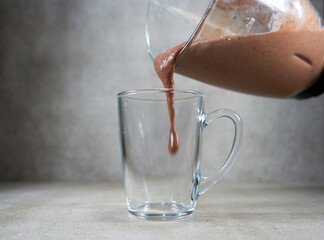 Red fruit smoothie is being poured to the glass cup