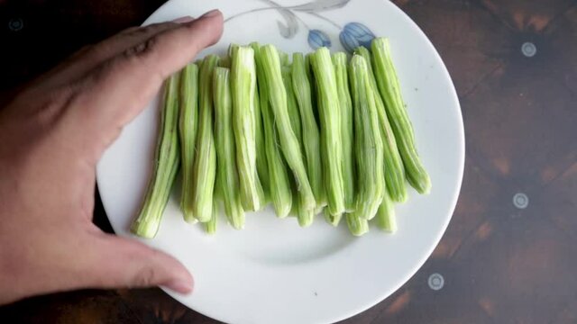 Chopped Moringa Oleifera rearranging in ceramic plate by hand