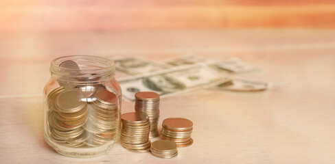 jar with coins and dollars on a wooden background
