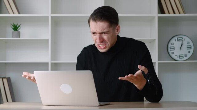 Portrait of shocked male businessman looking at laptop, takes off glasses and say What. Surprised and scared man on modern office interior background. Indignant and dissenting guy say no with disgust
