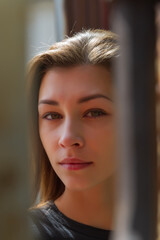 beautiful woman with loose hair looks through the fence, close-up.