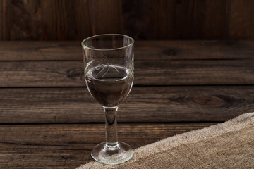 Glass of vodka with piece of cloth on an old wooden table. Angle view