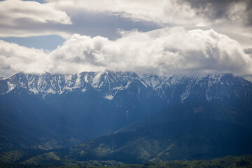 Heavy clouds over the Bucegi mountains in Romania during a spring day, as seen from the hills of Pestera village.
