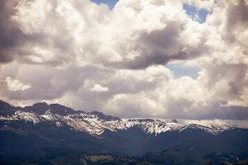Heavy clouds over the Bucegi mountains in Romania during a spring day, as seen from the hills of Pestera village.