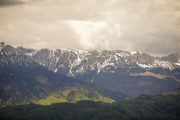 Naklejka premium Heavy clouds over the Bucegi mountains in Romania during a spring day, as seen from the hills of Pestera village in Transylvania.
